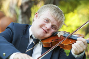 Ung mann med utviklingshemning spiller fiolin utendørs