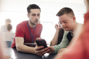 Ung mann med Down syndrom blir vist noe på en smarttelefon