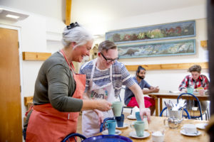 En mann og en dame forbereder varm drikke på en café